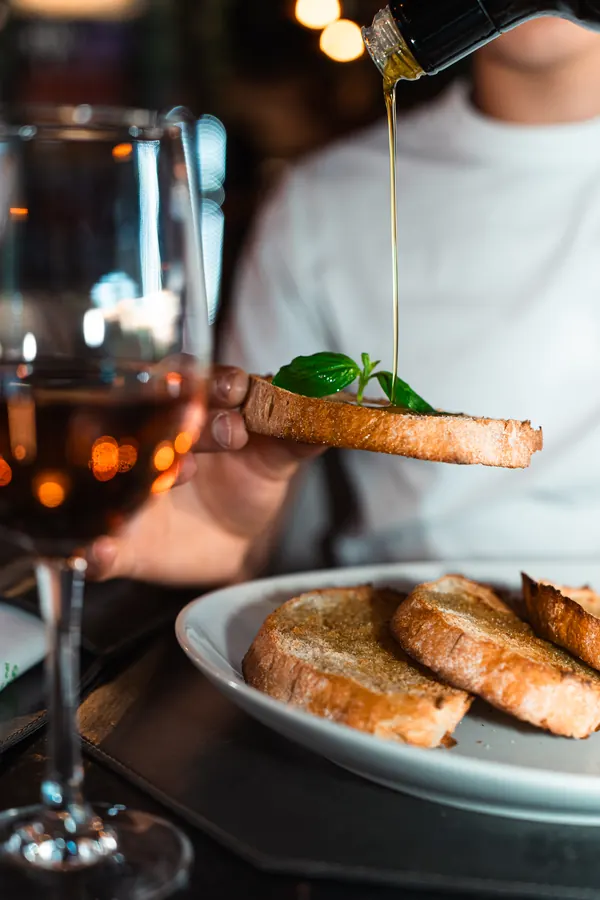 Olio extravergine versato sulla bruschetta, con un calice di rosato – Locanda degli Scaligeri, Verona