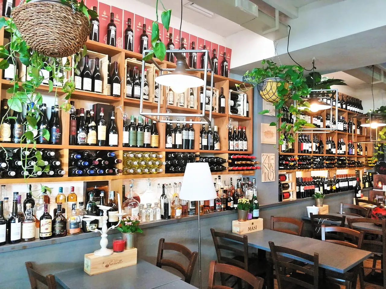 La sala della Locanda degli Scaligeri con la parete dei vini e i tavoli in legno, Verona